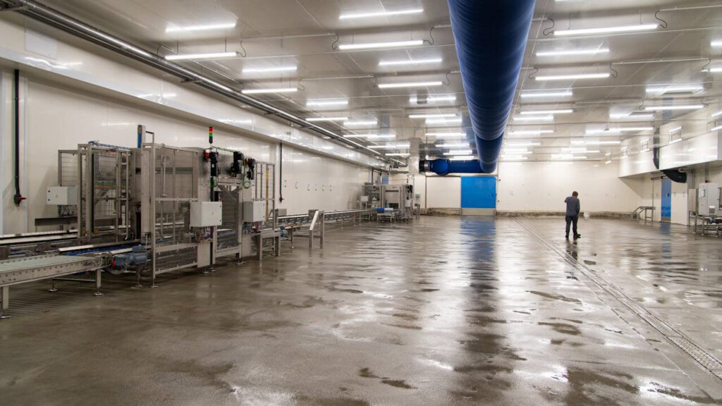 Spacious warehouse interior with machinery and a person inspecting the facility.