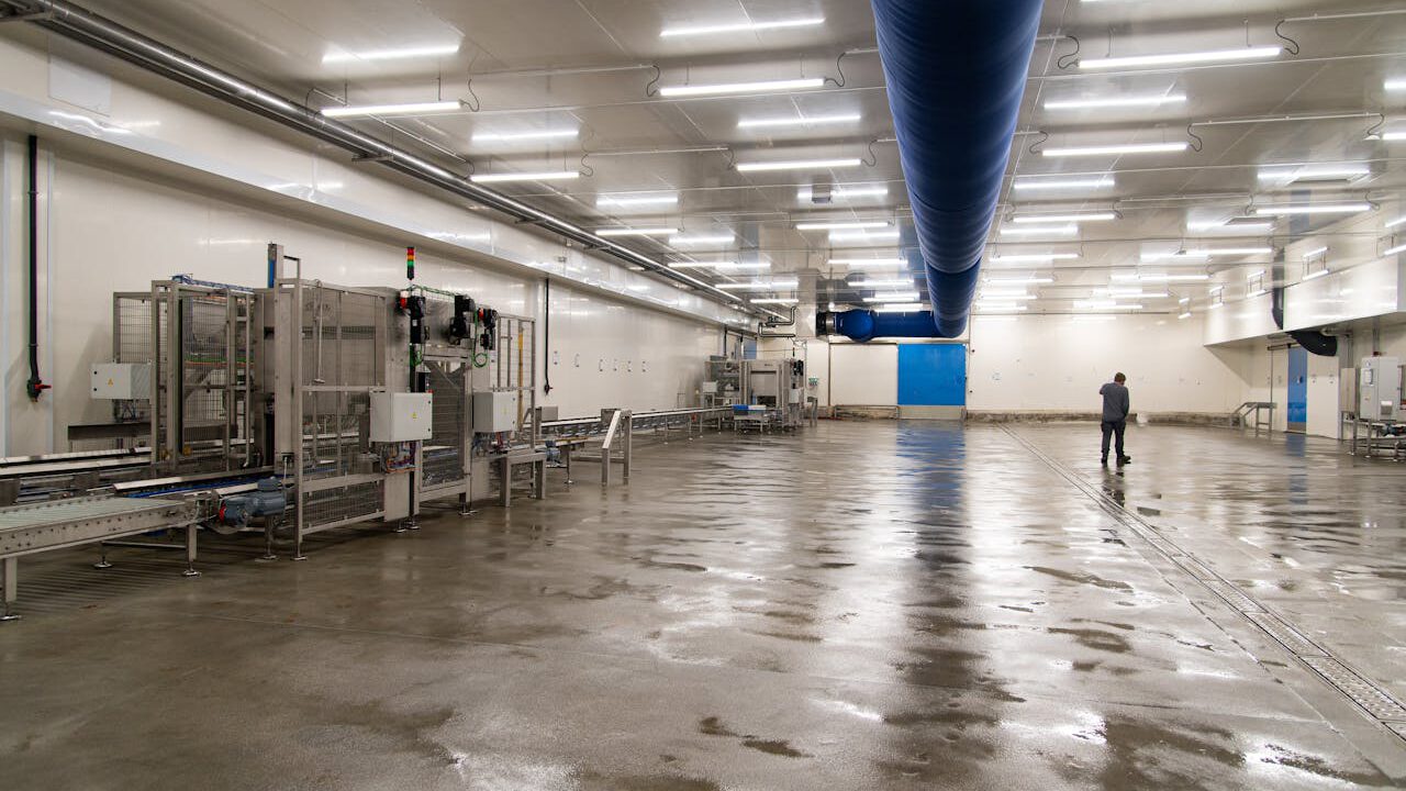 Spacious warehouse interior with machinery and a person inspecting the facility.